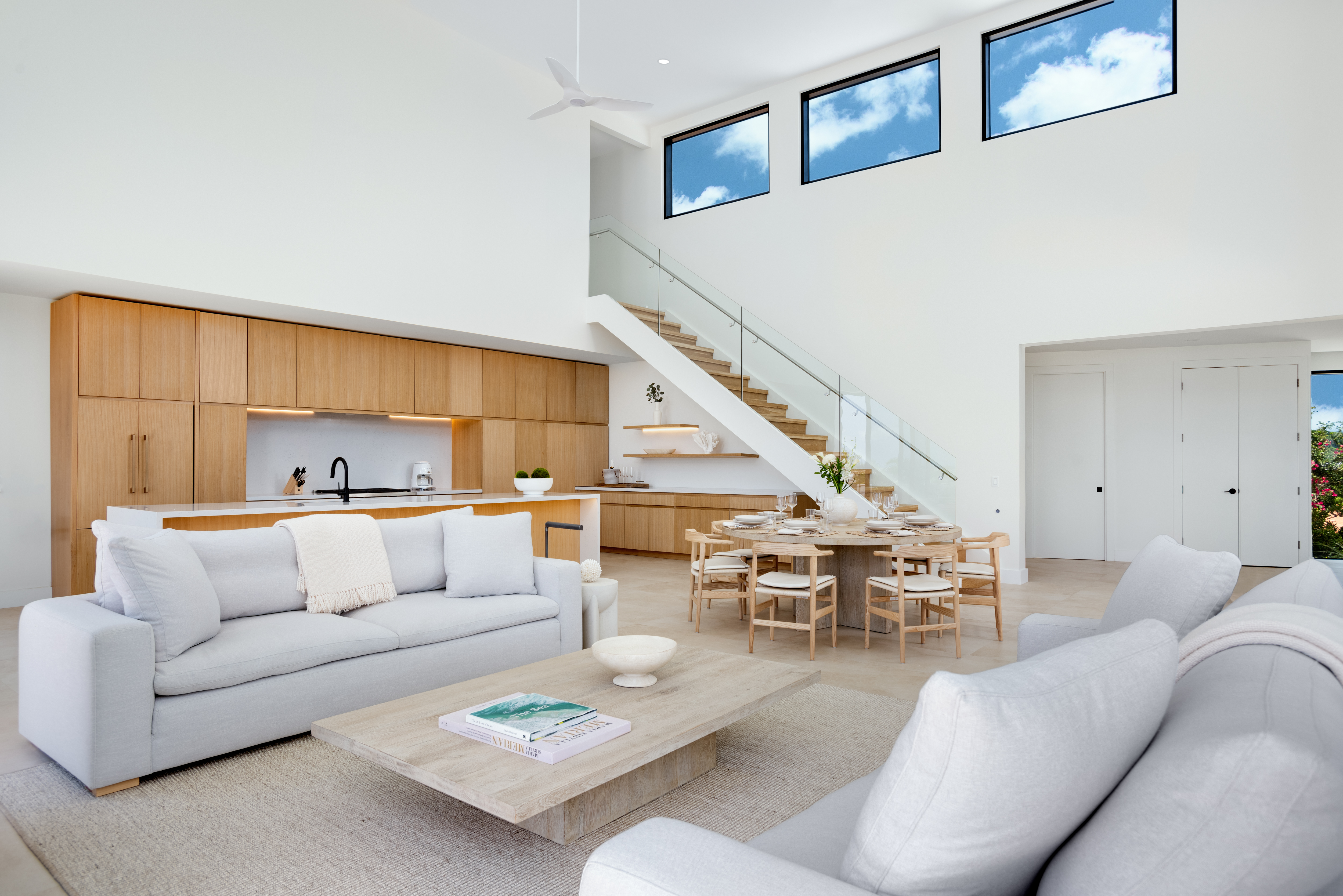 Open great room with 20-foot ceilings, oak kitchen, round dining table and floating staircase