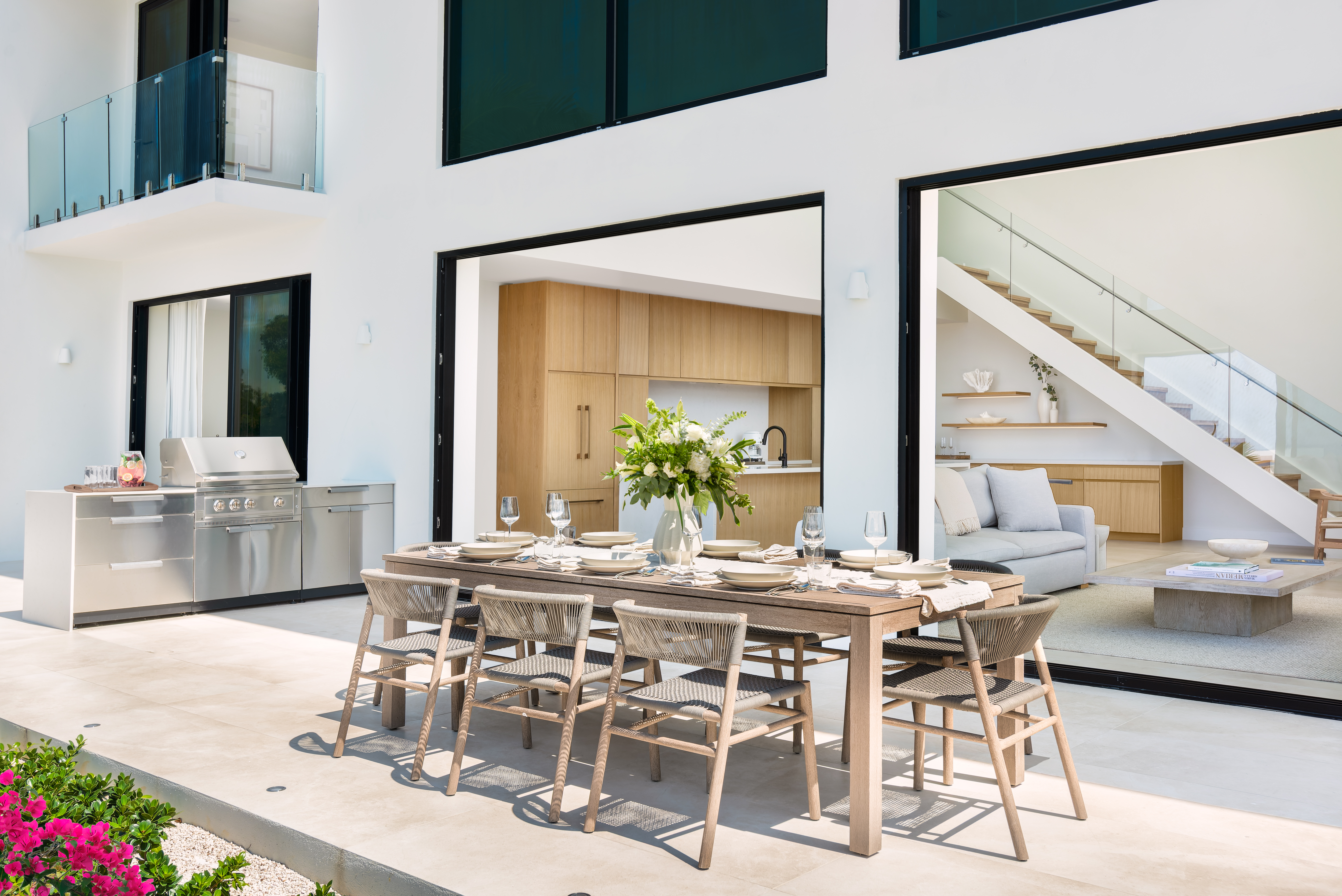 Covered outdoor dining table for eight beside the grill, opening to the kitchen