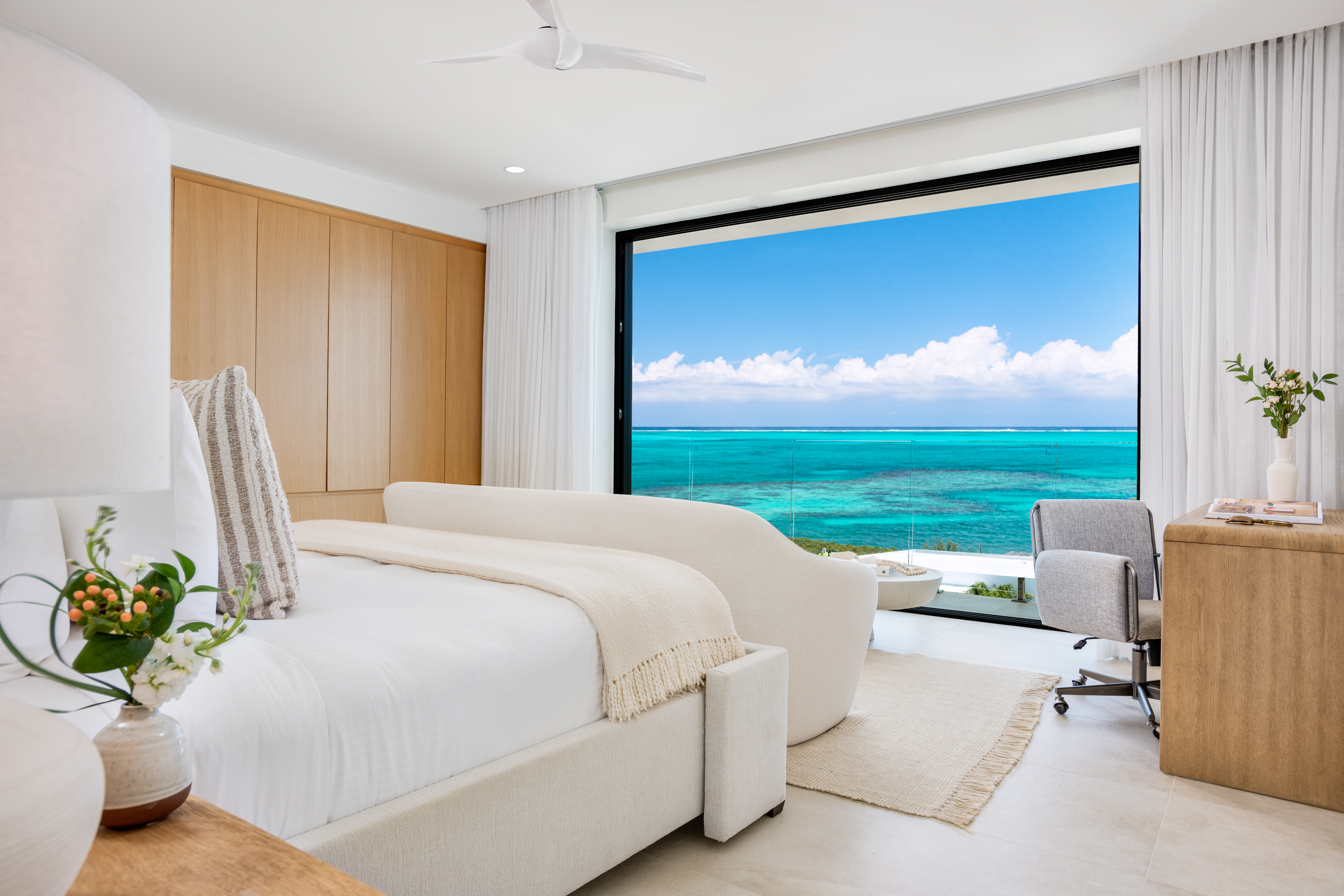 Master bedroom opening to a wall of glass over the turquoise reef at Beachwood Villa