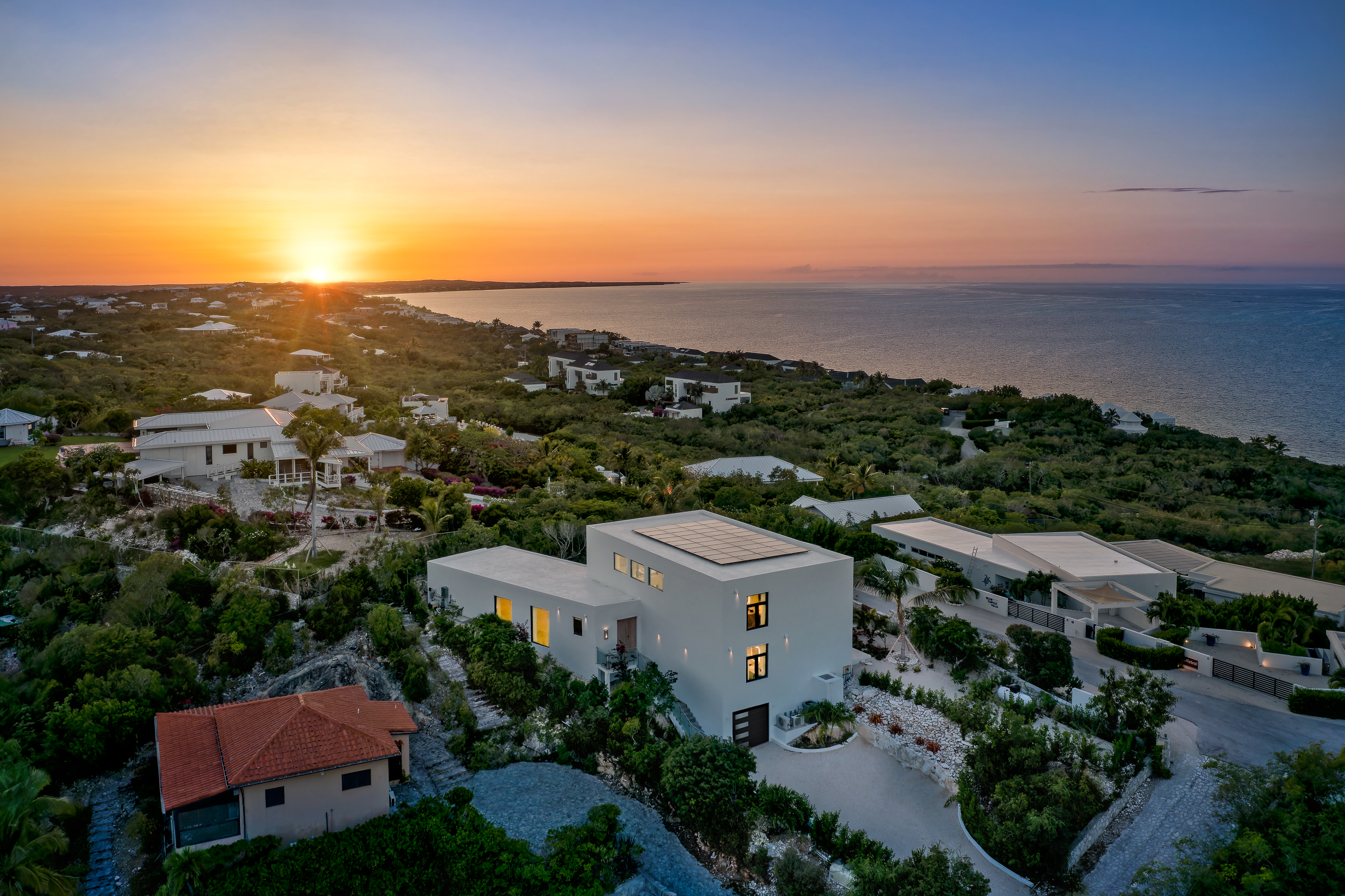 Beachwood Villa glowing on the hillside above the ocean at sunset