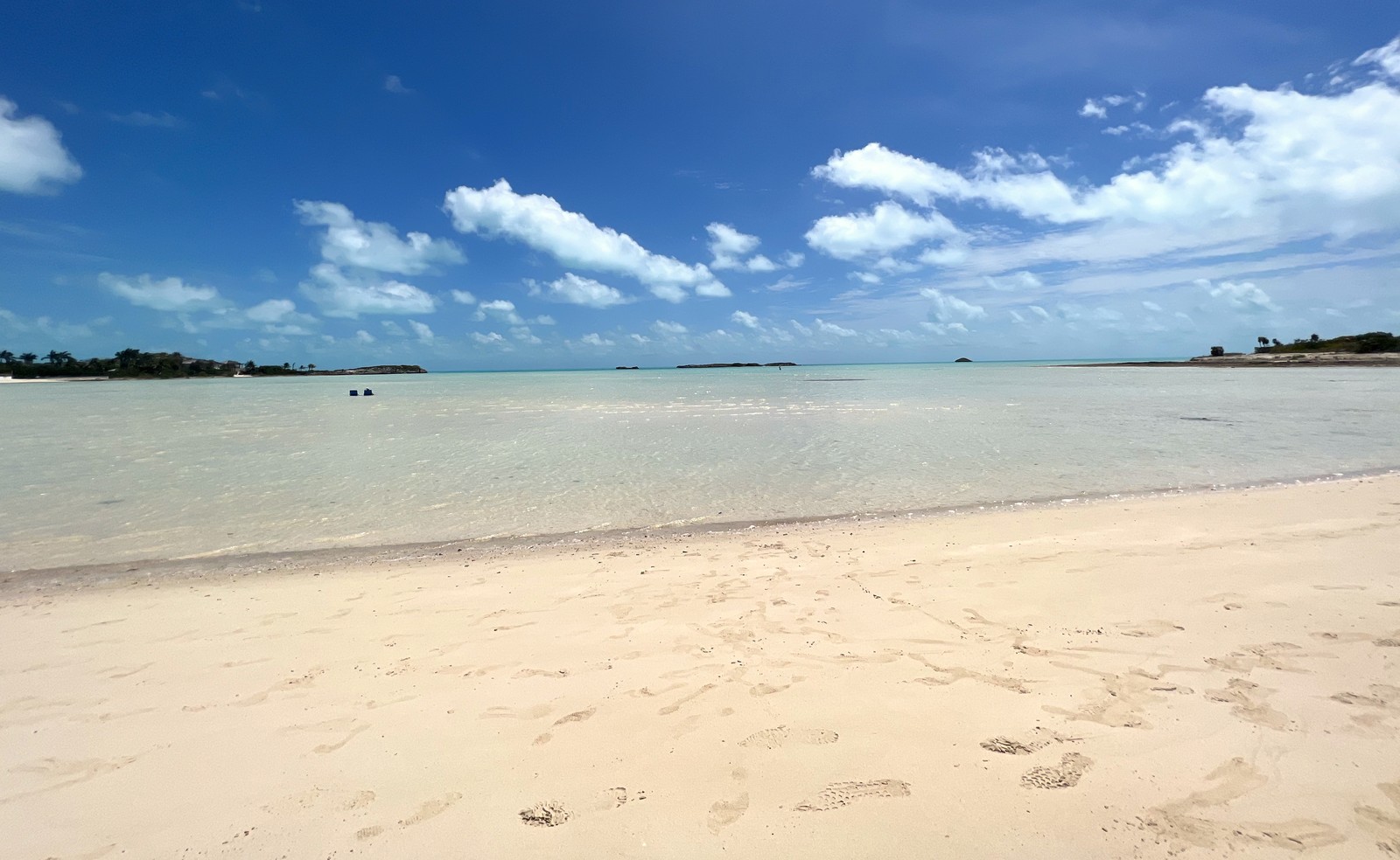 The calm shallow turquoise water and pale sand of Half Moon Bay with uninhabited cays on the horizon, Providenciales Turks and Caicos