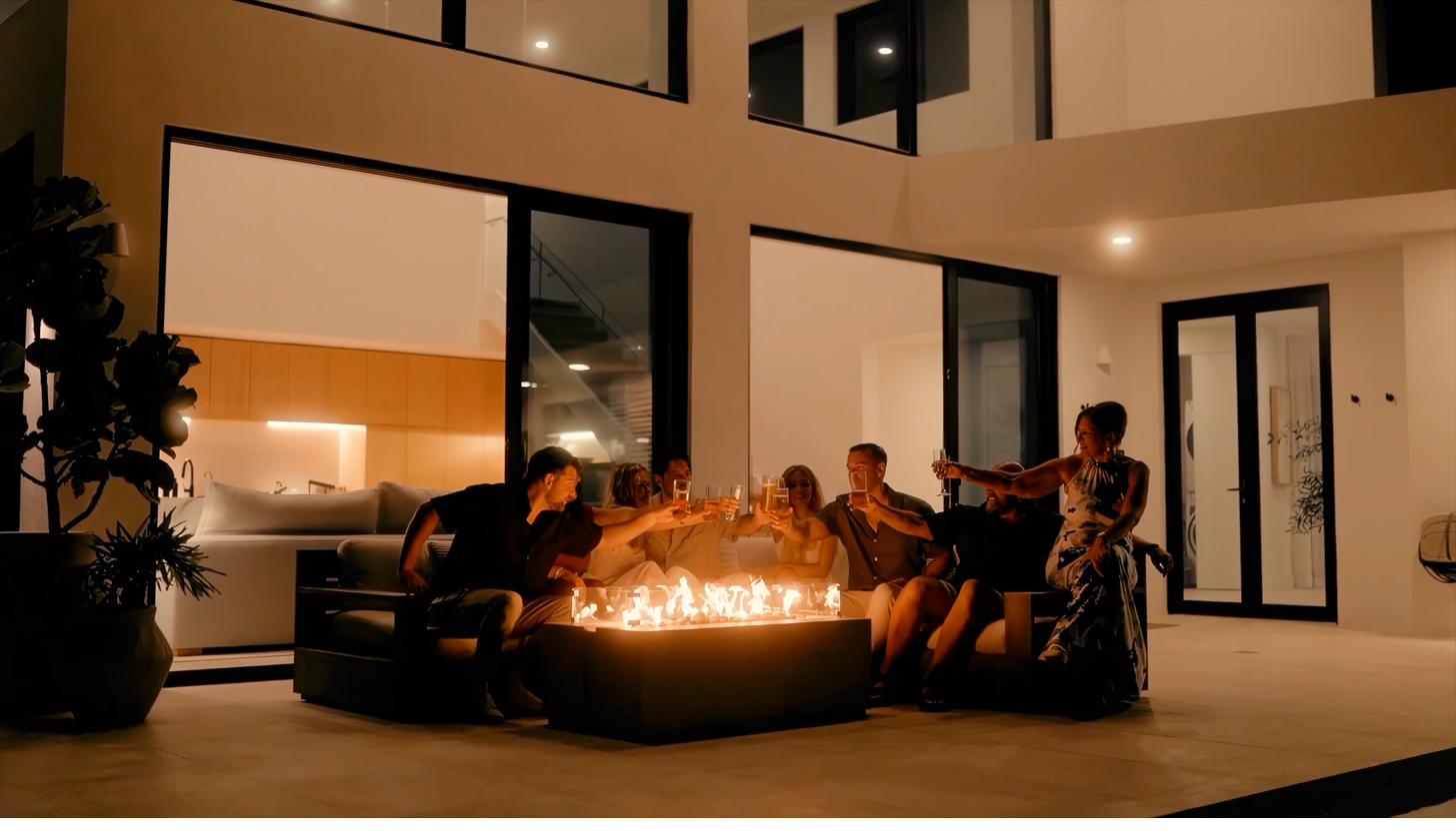 Group of friends raising glasses around the lit fire pit at Beachwood Villa for a milestone birthday celebration in Providenciales Turks and Caicos