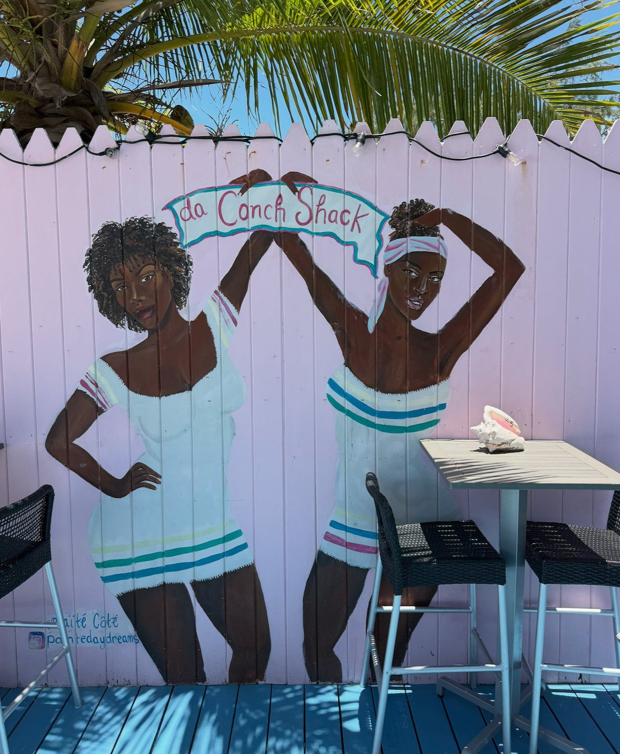 The painted da Conch Shack mural of two women on a lavender fence, Providenciales Turks and Caicos