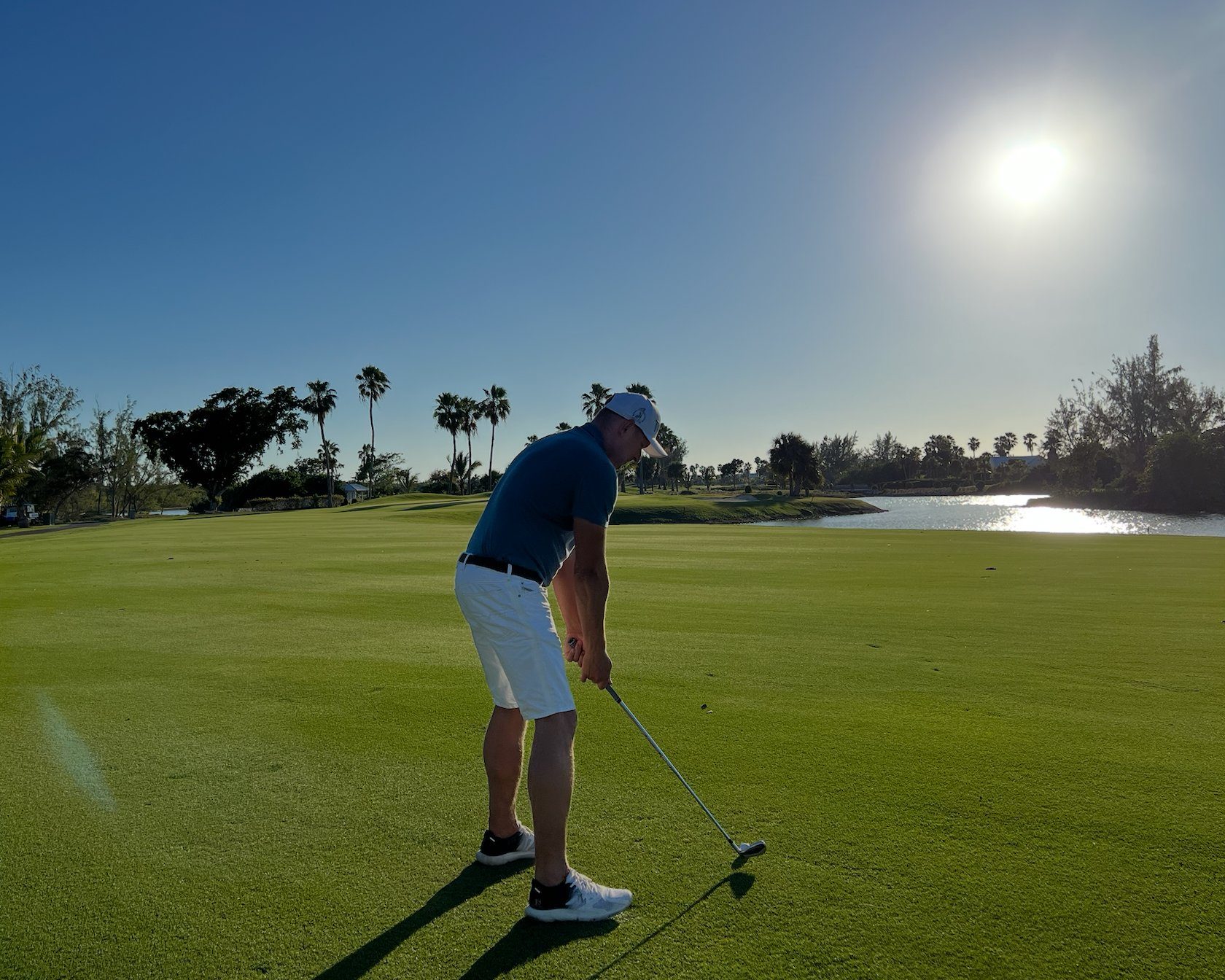 A golfer on a manicured fairway beside a lake at the Royal Turks and Caicos Golf Club, Providenciales