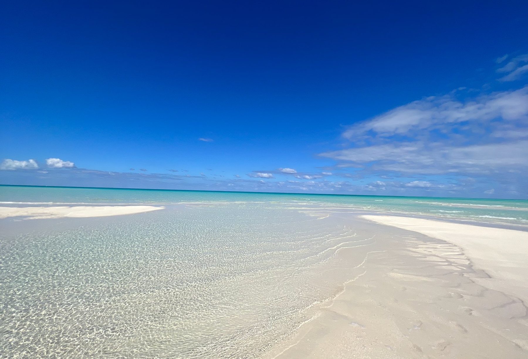 An empty white sandbar and clear shallow turquoise water under a blue sky in Providenciales, Turks and Caicos